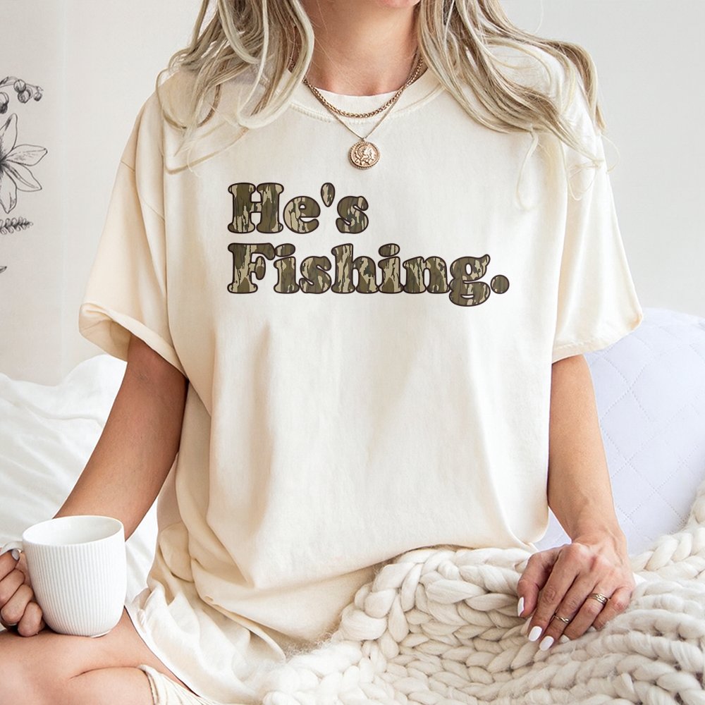 He's Fishing T-Shirt | Camo Print Text Graphic | 100% Cotton Premium Tee | Outdoorsman Gift for Fisherman